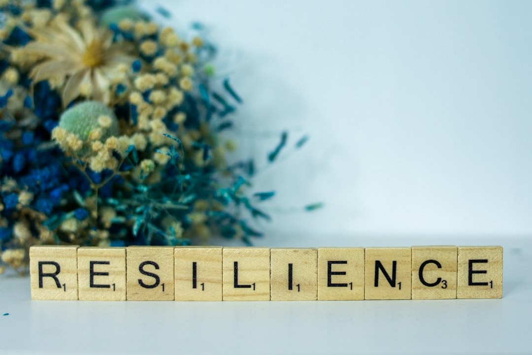 Wooden Scrabble tiles spelling 'RESILIENCE' on a white surface.